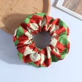 Detailed view of plush red and green argyle fabric scrunchie on wooden tray - Diamond Red Green Plaid