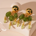 Detailed view of vintage gold earrings with olive green resin teardrop beads on a stone - Silver Needle - Green Teardrop Earrings