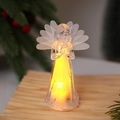 Dettaglio statuetta angelo LED trasparente con ali in rete su un tavolo per decorazione di Natale - Stile Preghiera