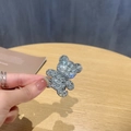 Macro di una molletta per capelli a orsetto con strass scintillanti su sfondo in legno - 1 pezzo / Bianco
