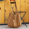 Minimalist brown canvas tote bag with large capacity and soft texture hanging on a chair - Brown