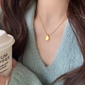 Collar de acero de titanio dorado con pequeño colgante ovalado en una modelo mujer - Collar-Placa de Letra Dorada Estilo Ovalado / Dorado