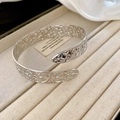 Macro shot of silver open cuff bracelet with intricate floral filigree on velvet tray - Silver Arm Cuff