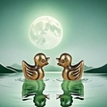Figuras de patos de bronce sobre agua bajo un paisaje de montaña a la luz de la luna - Pato amarillo