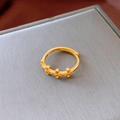 Nahaufnahme des vergoldeten Dreifach-Kreuz-Rings auf einer grauen Schmuckschatulle - Dreifach-Kreuz-Design (WR633) / Gold