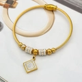 Détail d'un bracelet câble en acier doré avec pendentif losange en zircon et perles - Cube