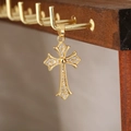 Dettaglio macro del ciondolo a croce dorata con zirconi su un supporto per gioielli - Stile Croce 24