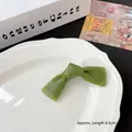 Green resin bow hair clip with vertical texture and 6.5cm length on ceramic plate - Kelp Seaweed Skewer