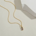 Dettaglio del ciondolo a melanzana dorata con zirconi viola e verdi su catena - Melanzana in Zircone Viola