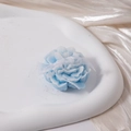 Detailed view of flower-shaped blue scented candle with white ribbon on a stone tray - Blue