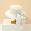 Elegant beige woven straw sun hat with floral ribbon bow displayed on a golden stand - M / Milky White