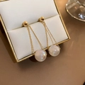 Nahaufnahme goldener Doppelkreis-Perlenohrringe in einer luxuriösen beigen Schmuckschachtel - Feine Kette Perlen Stil / Gold