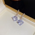 Vista macro de pendientes geométricos de cristal chapados en oro en un estuche - Dorado