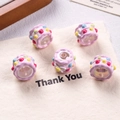 Detail shot of five pink resin cake-shaped beads for DIY jewelry making on a fabric bag - Transparent + Pink Edge + Red/Yellow/Blue Dots