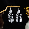 Detalle de pendientes bohemios con borlas y cuentas rosas en una rama de madera real - E6100-23 Punta de Color