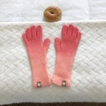 Detailed view of pink orange gradient knit gloves with ribbed texture and woven cuff label - Peach