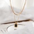 Macro view of double-layer titanium necklace with rectangular black pendant and gold frame - Gold Double Layer Black Square Necklace