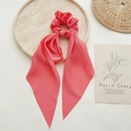 Detail of coral satin scrunchie with long ribbons on a marble tray with artistic decor - Pink