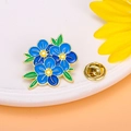 Broche de esmalte con flores azules, estambres amarillos y hojas verdes sobre cerámica - Floral Azul / Azul