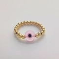 Macro shot of 18K gold beaded ring with pink evil eye glass bead on white background - Size 7 (Elastic) / Pink