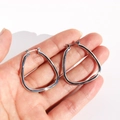 Triangle geometric hoop earrings in polished silver finish held by hand for scale - White Gold
