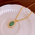 Détail d'un collier vintage en forme de gourde avec pierre verte sur plat en céramique - Collier N° 67 - Or - Ovale (plaqué Or Véritable)