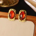 Detail of vintage gold earrings with large faceted red gemstone and hammered metal texture - Gold Red Rectangular Gemstone Stud Earrings (1 Pair)