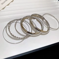 Detail von silbernen Armreifen im Set mit gedrehten und strukturierten Mustern auf einem Tablett - 8-Teiliges Set / Silber