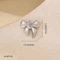 Colgante de lazo plateado con gema de corazón en textura beige con medidas de 1,3 x 1,5 cm - Oro Blanco Estilo Tres (Piedra Blanca)