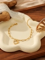 Dettaglio del bracciale dorato a cuore con cristalli su un vassoio di ceramica bianca - Bracciale a Cuore Vuoto Con Zirconi (ZHB1052金)