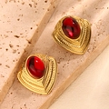 Detalle de pendientes vintage de corazón con piedra roja sobre fondo de gres beige - Rojo
