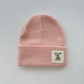 Detailed close-up of a pink knit beanie featuring a cute bear patch and soft texture - One Size (Ages 3+) / Orange Pink