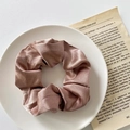 Elegant dusty pink satin scrunchie with soft pleated texture on white ceramic plate - Satin Coffee