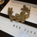 Primer plano de pulsera abierta de flores doradas vintage con texturas de pétalos finos - Flor de Oro Envejecido