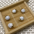 Five oval white marble natural stone charms with gold metal loops on a bamboo tray - Howlite