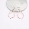 Macro detail of rose gold waterdrop hollow earrings on a white marble display - Rose Gold