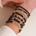 Detail of layered black and gold beaded bracelets with crystal acrylic accents on a model - 7-Piece Set / Black/Gold (SY0794-1)