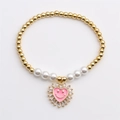 Golden stretch bracelet with pearls and pink heart eye pendant on a clean gray background - Pink