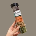 Colorful spiral hair ties in a transparent storage tube held by hand - Dark Multi-Color 100Pcs (Bottled)