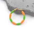 Detail view of gold-plated bamboo hoop earrings with vibrant orange and green enamel drip - Orange