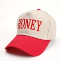 Dettaglio del ricamo HONEY su un cappellino da baseball bicolore beige e rosso - Rosso
