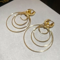 Gros plan de boucles d'oreilles dorées multicouches avec accents de diamants étincelants - Doré