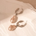 Detailed shot of irregular champagne pearl drop earrings on a white mineral stone background - Silver Geometric Pearl Style