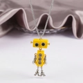 Detailed macro shot of a yellow robot pendant with movable limbs on a metal chain - Yellow
