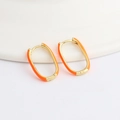 Macro detail of gold U-shaped oval hoop earrings with vibrant orange enamel coating - Orange