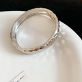 Dettaglio macro della texture martellata argentata e della cerniera su un bracciale di metallo - Stile con Texture Trapuntata / Argento