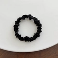 Top view of a black soft fabric scrunchie with elegant pleats on a white ceramic plate - Small / Black