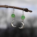 Detalle de pendientes de luna plateados con piedras verdes colgados de una rama - Verde (Estilo de Luna Creciente y Piedra Redonda)