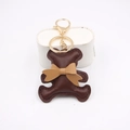 Dettaglio portachiavi a forma di orsetto in pelle PU marrone scuro con fiocco e gancio d'oro - Marrone