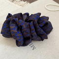 Close-up of leopard print scrunchie with blue spots and ruffled silk texture - Brown Blue Bright Leopard Twisted Clip